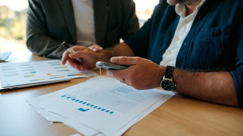 Consulente e imprenditore PMI che esaminano documenti di finanza sostenibile e certificazioni ESG in ufficio moderno